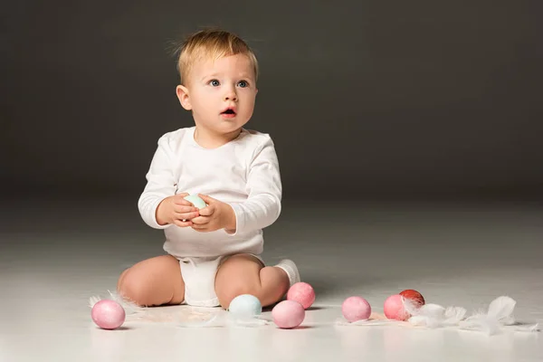 Bambino con la bocca aperta, tenendo uovo di Pasqua su sfondo nero — Foto stock