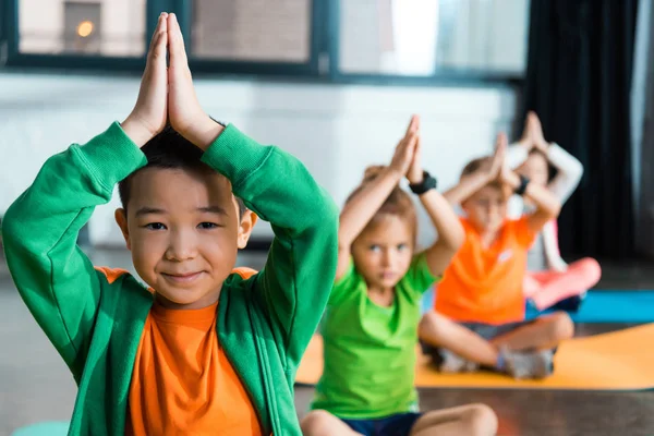 Concentration sélective des enfants multiculturels avec les mains serrées étirant dans le centre sportif — Photo de stock