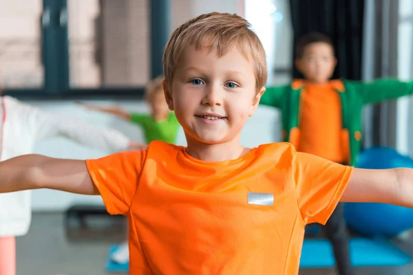 Concentration sélective de garçon souriant et travaillant avec les mains tendues dans la salle de gym — Photo de stock