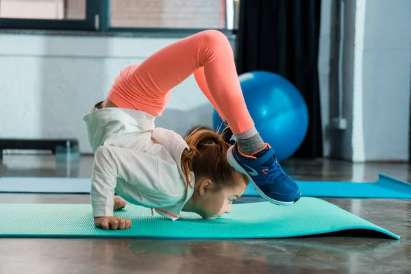 Selective focus of child stretching on fitness mat in gym — Stock Photo