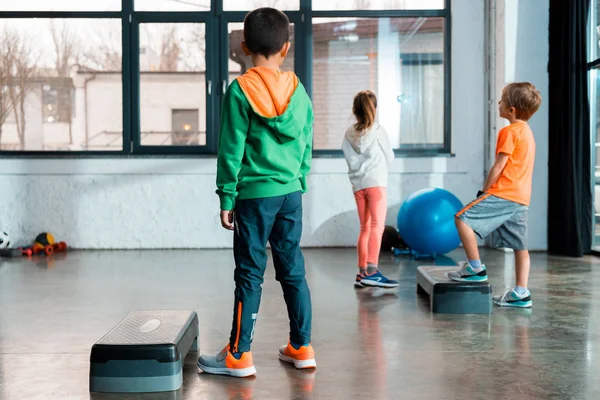 Vista posteriore dei bambini accanto alle piattaforme passo in palestra — Foto stock