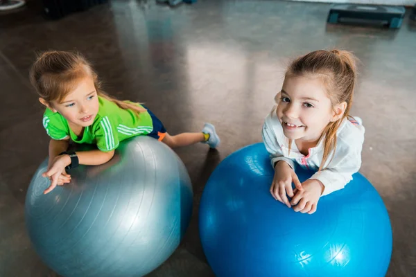 Blick aus der Vogelperspektive auf Kinder, die sich in der Turnhalle an Fitnessbälle lehnen — Stockfoto