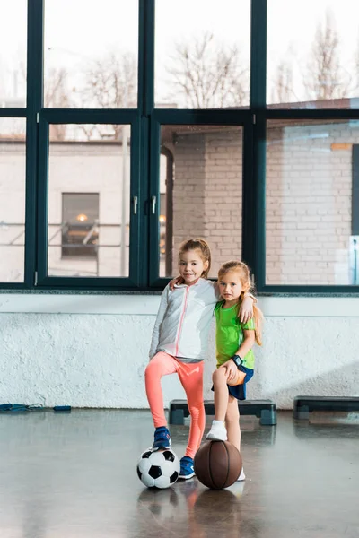 Niños abrazando y poniendo las piernas en las bolas en el gimnasio - foto de stock