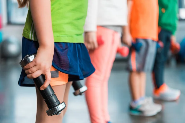 Cropped view of kids holding dumbbells in sports center — Stock Photo