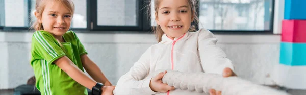 Vue recadrée d'enfants jouant au remorqueur de guerre en salle de gym, prise de vue panoramique — Photo de stock