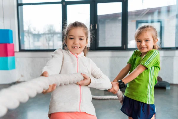 Selective focus of children smiling and playing tug of war in sports center — Stock Photo