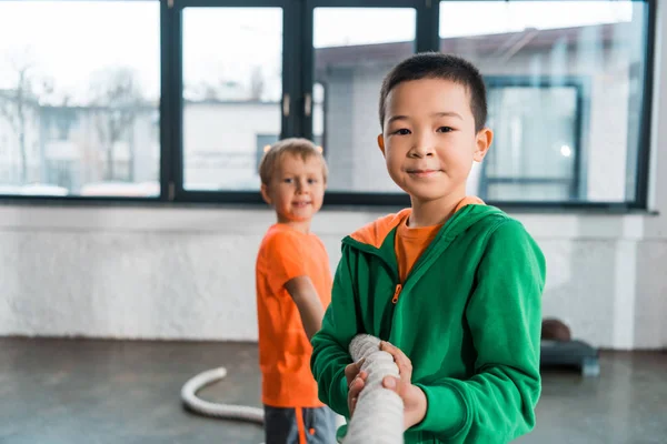 Focus selettivo dei bambini multiculturali che giocano a tiro alla fune nel centro sportivo — Foto stock