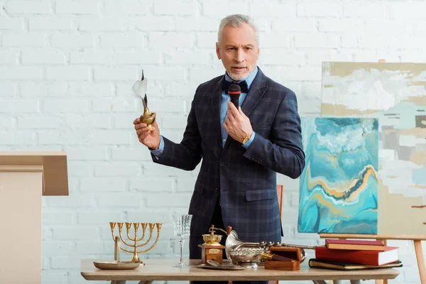 Handsome auctioneer talking with microphone and holding feather pen during auction — Stock Photo