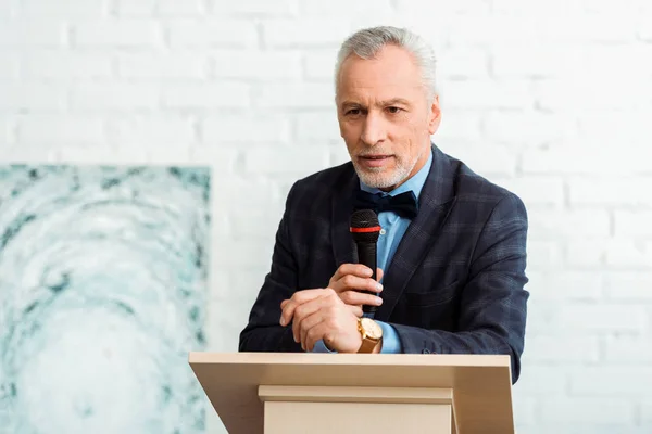 Schöner Auktionator im Anzug spricht während der Auktion mit Mikrofon — Stockfoto