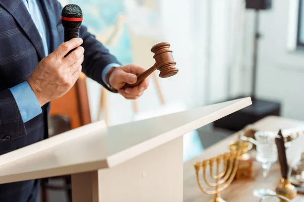 Cropped view of auctioneer in suit talking with microphone and holding gavel during auction — Stock Photo