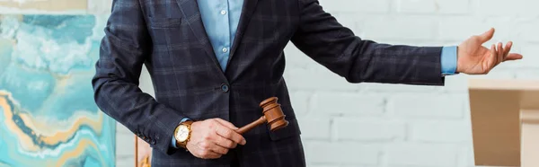 Panoramic shot of auctioneer holding gavel and pointing with hand during auction — Stock Photo