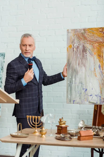 Auctioneer talking with microphone and holding picture during auction — Stock Photo
