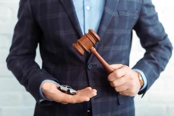 Cropped view of auctioneer holding model of car and gavel — Stock Photo