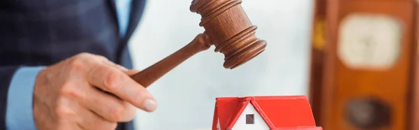 Panoramic shot of auctioneer hitting model of house with gavel during auction — Stock Photo