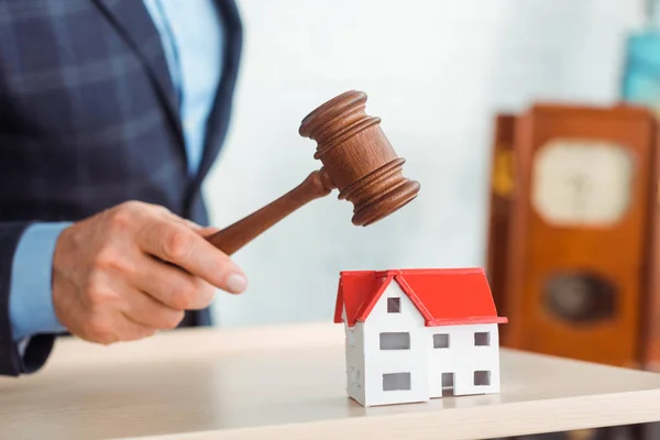 Cropped view of auctioneer hitting model of house with gavel during auction — Stock Photo