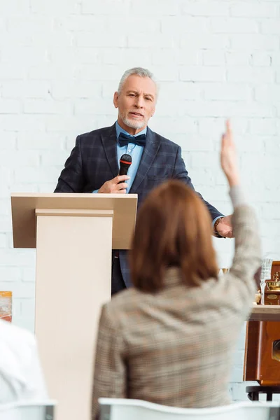 Selective focus of auctioneer talking with microphone and looking at buyer during auction — Stock Photo