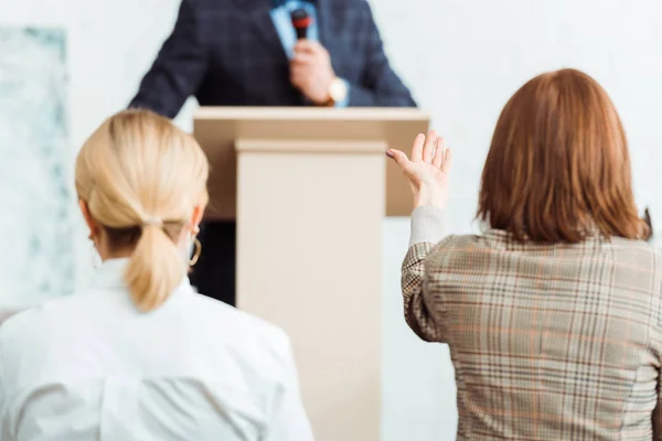 Back view of buyers looking at auctioneer and pointing with hand during auction — Stock Photo