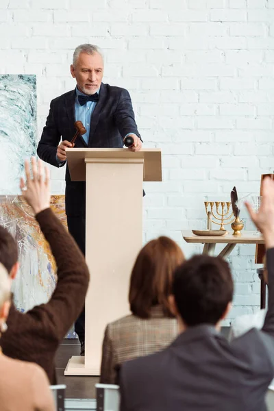 Selective focus of auctioneer holding gavel and pointing with finger at buyer during auction — Stock Photo