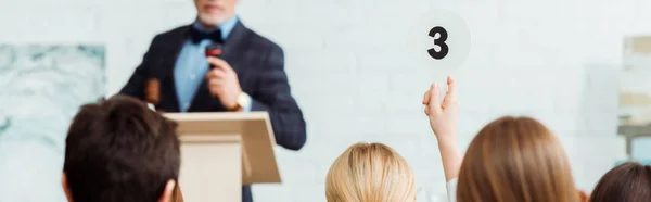 Panoramic shot of buyer showing auction paddle with number three to auctioneer during auction — Stock Photo