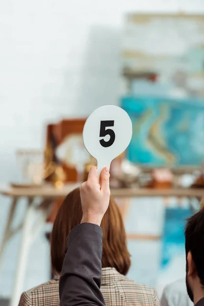 Cropped view of buyer showing auction paddle with number five during auction — Stock Photo