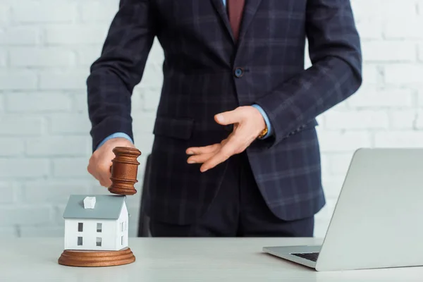 Cropped view of auctioneer holding gavel and pointing with hand at model of house — Stock Photo