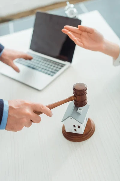 Cropped view of auctioneer hitting with gavel model oh house and woman pointing with hand — Stock Photo