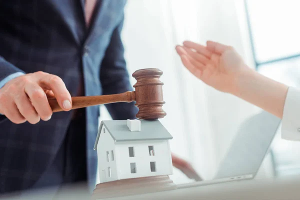 Cropped view of auctioneer hitting with gavel model oh house and woman pointing with hand — Stock Photo