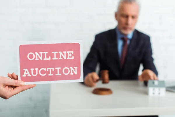 Cropped view of woman holding card with online auction lettering and auctioneer holding gavel — Stock Photo