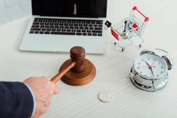 Cropped view of auctioneer hitting with gavel near shopping trolley with car and key — Stock Photo