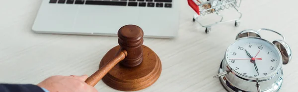 Panoramic shot of auctioneer hitting with gavel near alarm clock — Stock Photo