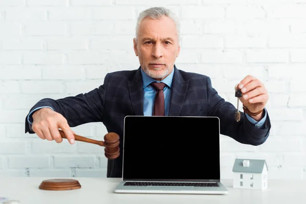 Auctioneer holding gavel and key near laptop with copy space — Stock Photo