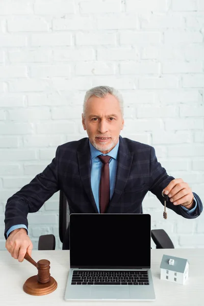 Auctioneer holding gavel and key near laptop with copy space — Stock Photo