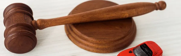 Panoramic shot of wooden gavel and model of car on table — Stock Photo