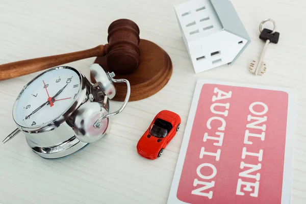 Card with online auction lettering, gavel, alarm clock, key, models of car and house — Stock Photo