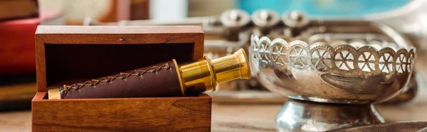 Panoramic shot of spyglass in box and ancient ashtray on table — Stock Photo