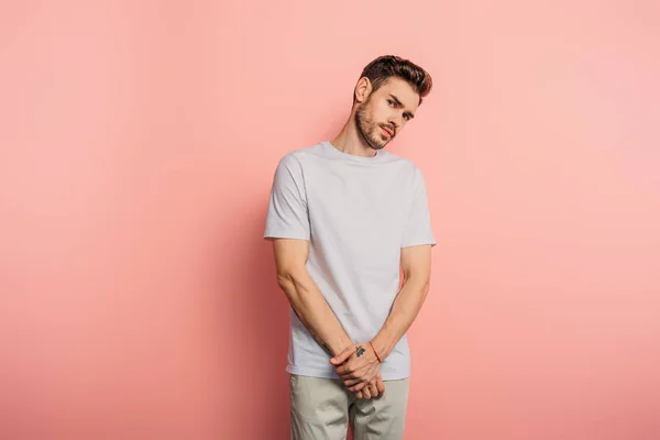 Offended young man looking at camera while standing on pink background — Stock Photo