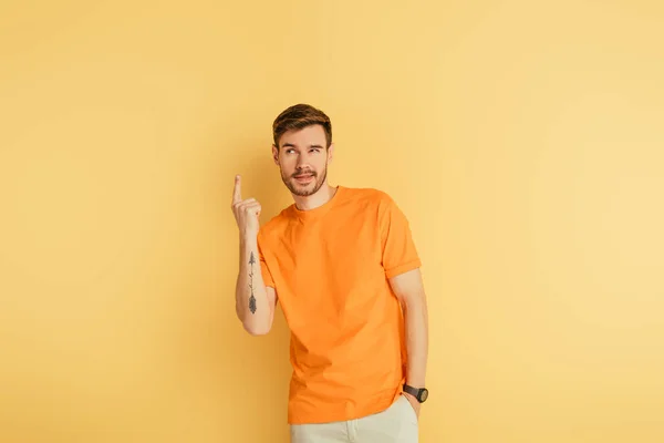 Kniffliger junger Mann zeigt Ideengeste auf gelbem Hintergrund — Stockfoto