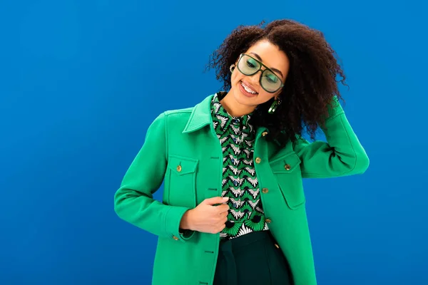 Smiling african american woman in stylish jacket isolated on blue — Stock Photo