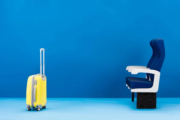 Sac de voyage jaune et sièges sur fond bleu — Photo de stock
