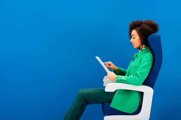 Vista lateral da mulher afro-americana usando tablet digital isolado em azul — Fotografia de Stock