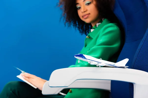 Foco seletivo de modelo de avião e mulher americana africana olhando para ele isolado em azul — Fotografia de Stock