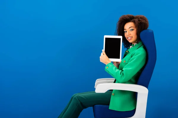 Femme afro-américaine souriante tenant tablette numérique isolé sur bleu — Photo de stock