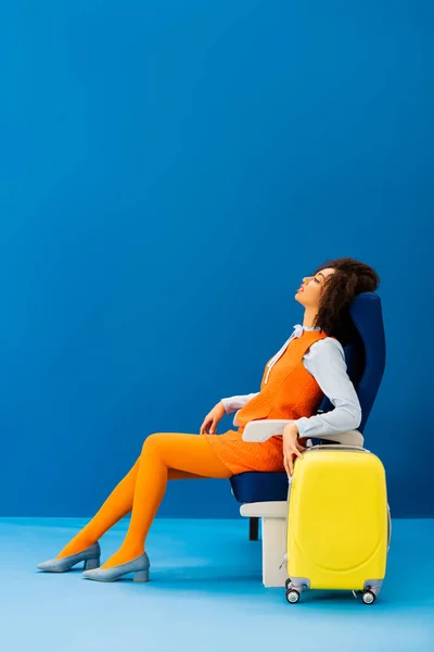 Side view of african american in retro dress sleeping in seat on blue background — Stock Photo