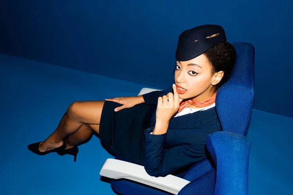 Vue grand angle de l'agent de bord afro-américain assis sur un siège sur fond bleu — Photo de stock