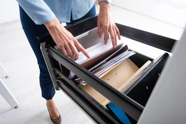 Vista ritagliata della donna d'affari che cerca il fascicolo nella cartella di carta nel driver aperto del gabinetto — Foto stock