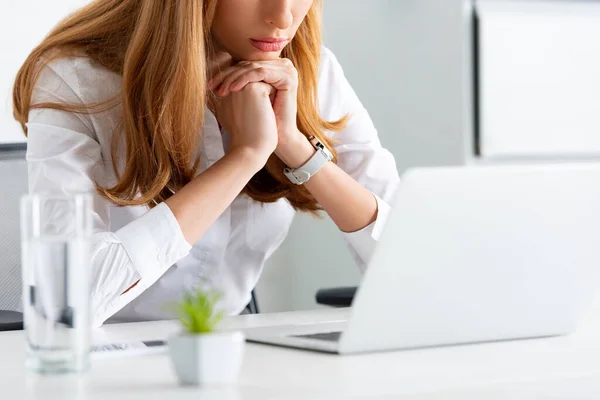 Cropped view of businesswoman sitting at table with laptop and glass of water — Stock Photo