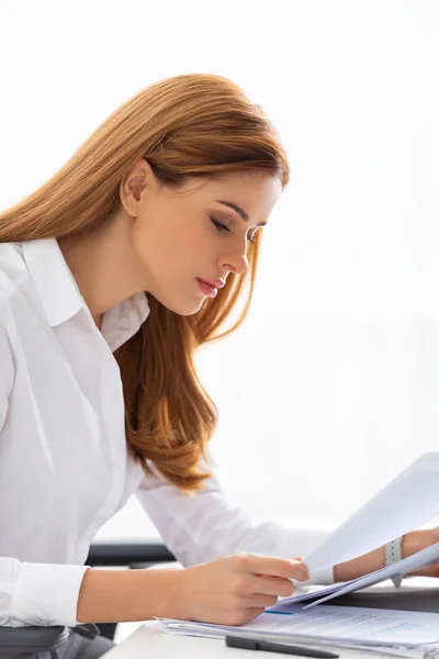 Side view of attractive businesswoman holding dossier near documents on table — Stock Photo