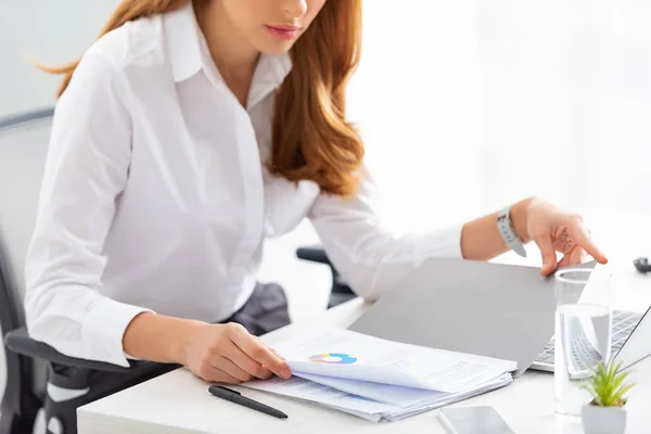 Обрезанный взгляд на деловую женщину, работающую с документами и графиком за столом — стоковое фото
