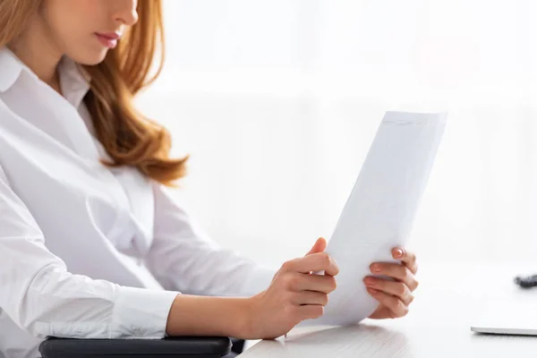 Ausgeschnittene Ansicht einer Geschäftsfrau, die Papiere mit Diagrammen am Tisch hält — Stockfoto