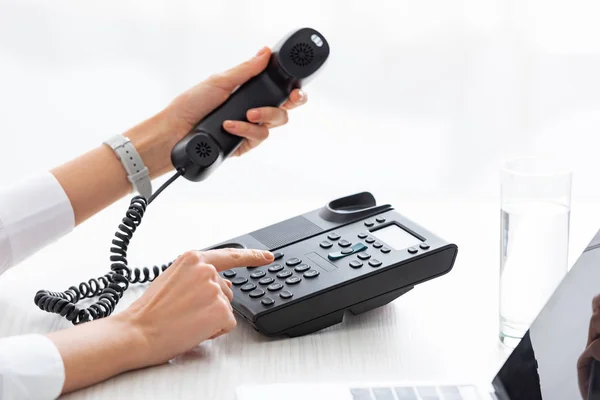 Vista cortada de empresária usando telefone perto de vidro de água e laptop na mesa — Fotografia de Stock